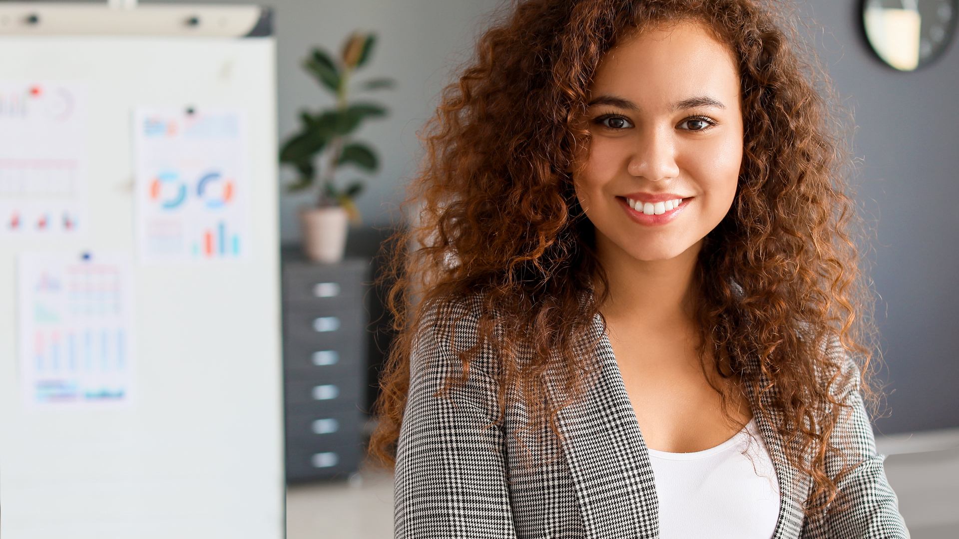 Woman smiling into camera in bureau surrounding
