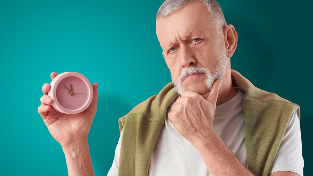 older man holding a clock